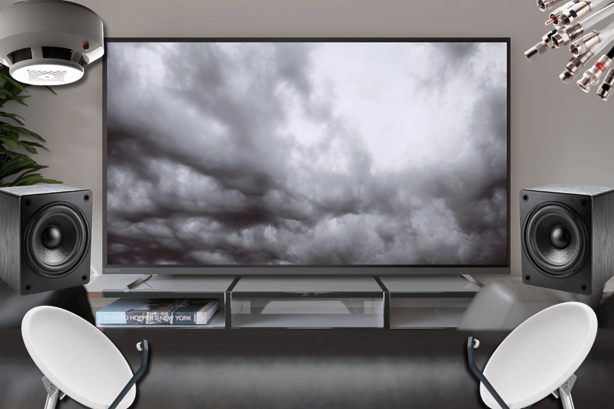 A modern home entertainment setup featuring a large TV, two speakers on either side, a satellite dish, and a smoke detector above depicting examples of low voltage installations.